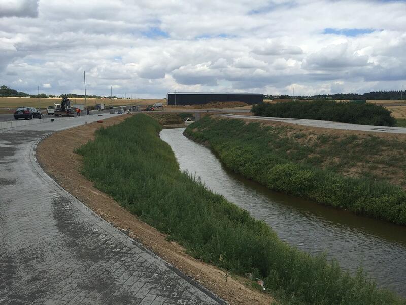 Ein Fluss verläuft durch ein Feld, angrenzend an eine Straße.