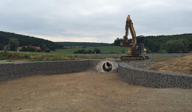 Ein großer Bagger ist im Einsatz, um an einer großen Betonwand zu arbeiten.