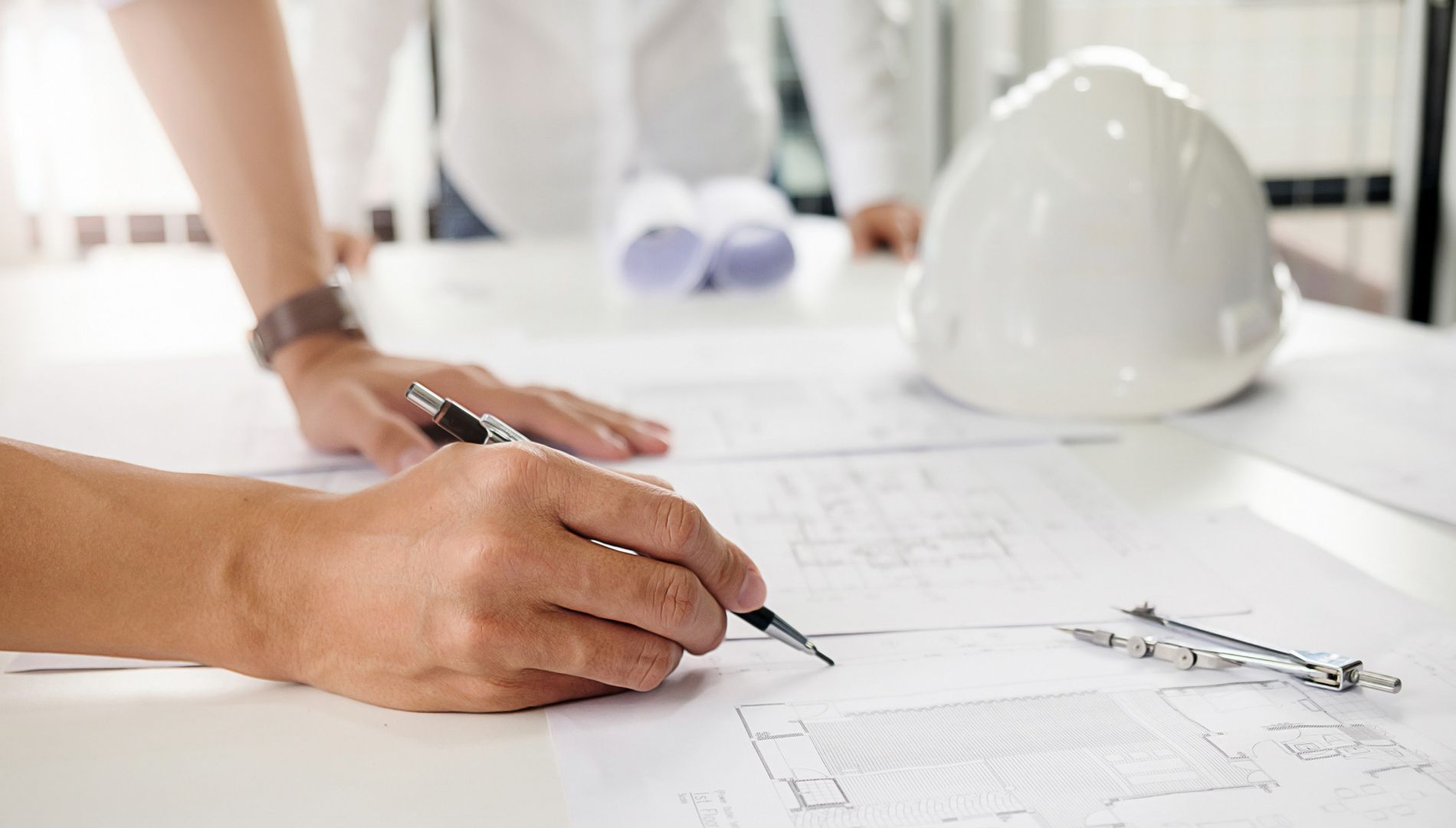 Eine Person mit einem Schutzhelm schreibt auf ein Blatt Papier.